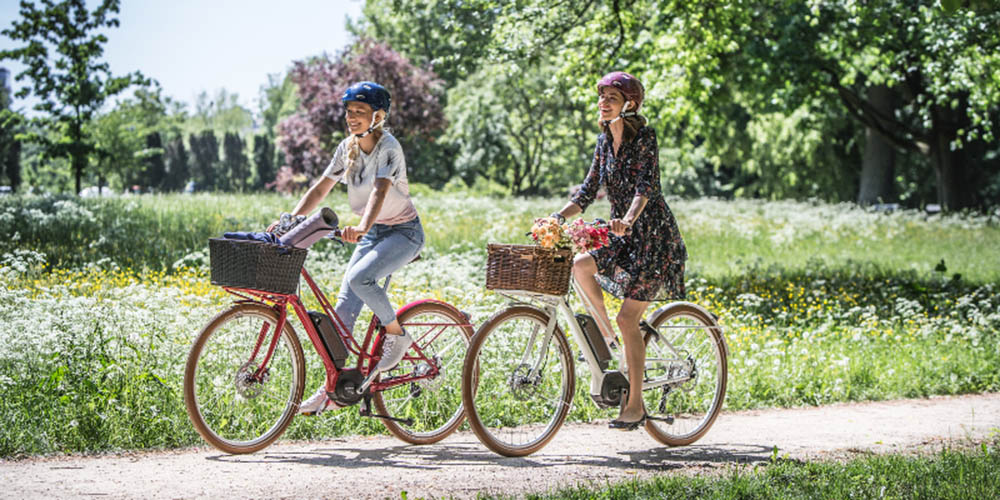 Twee dames rijden op de fiets in de zon